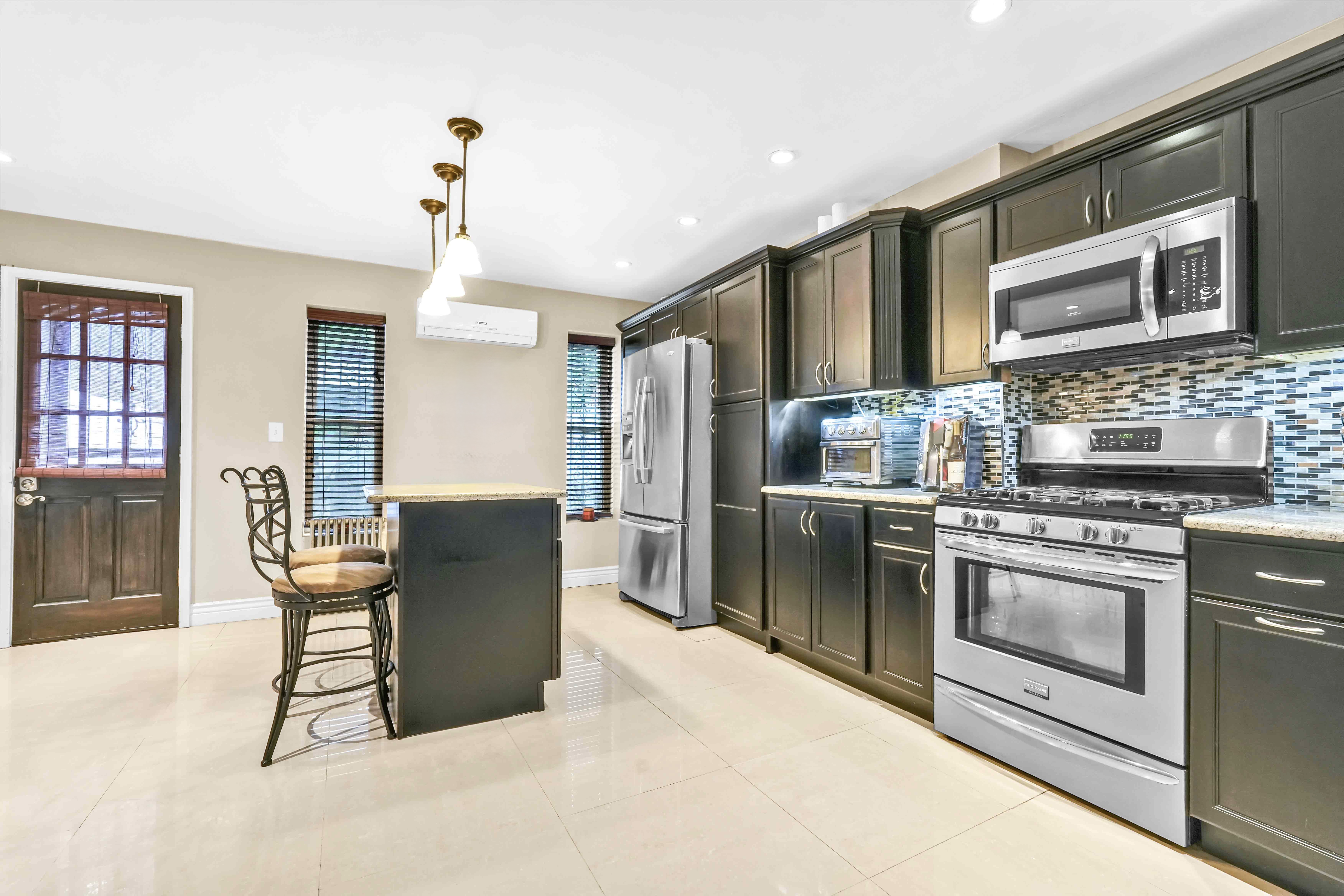 519 Monroe Street Brooklyn, NY 11221 - Photo 35 of 55 a kitchen with stainless steel appliances granite countertop a stove top oven a sink dishwasher a dining table and chairs with wooden floor