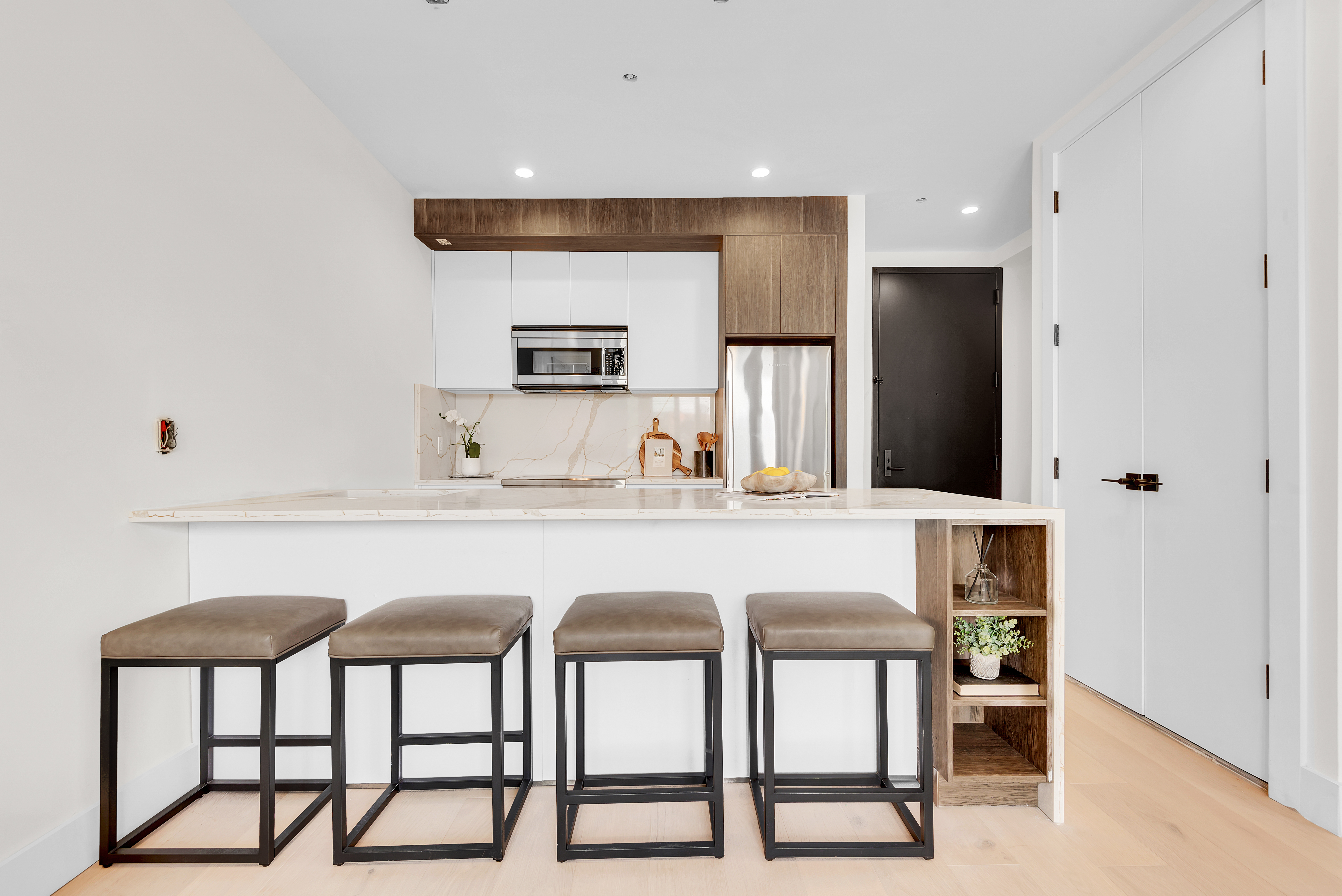 156 Somers Street, Unit 6AB Brooklyn, NY 11233 - Photo 4 of 8 a kitchen with stainless steel appliances kitchen island a table chairs in it and wooden floors
