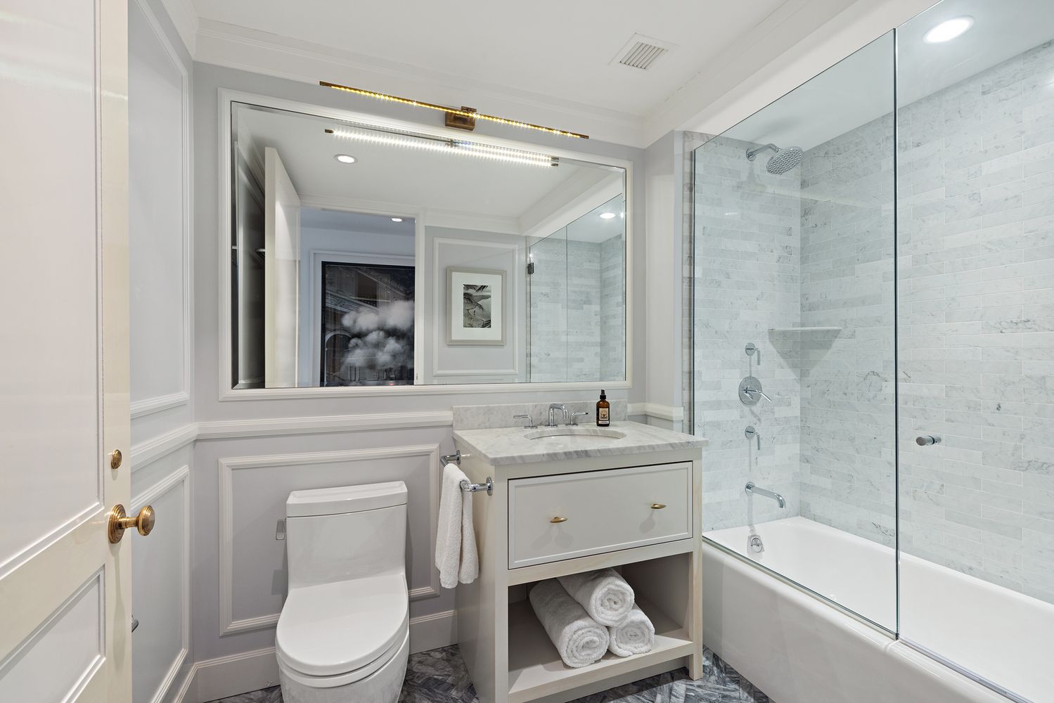 a bathroom with a sink a toilet a mirror a vanity and bathtub