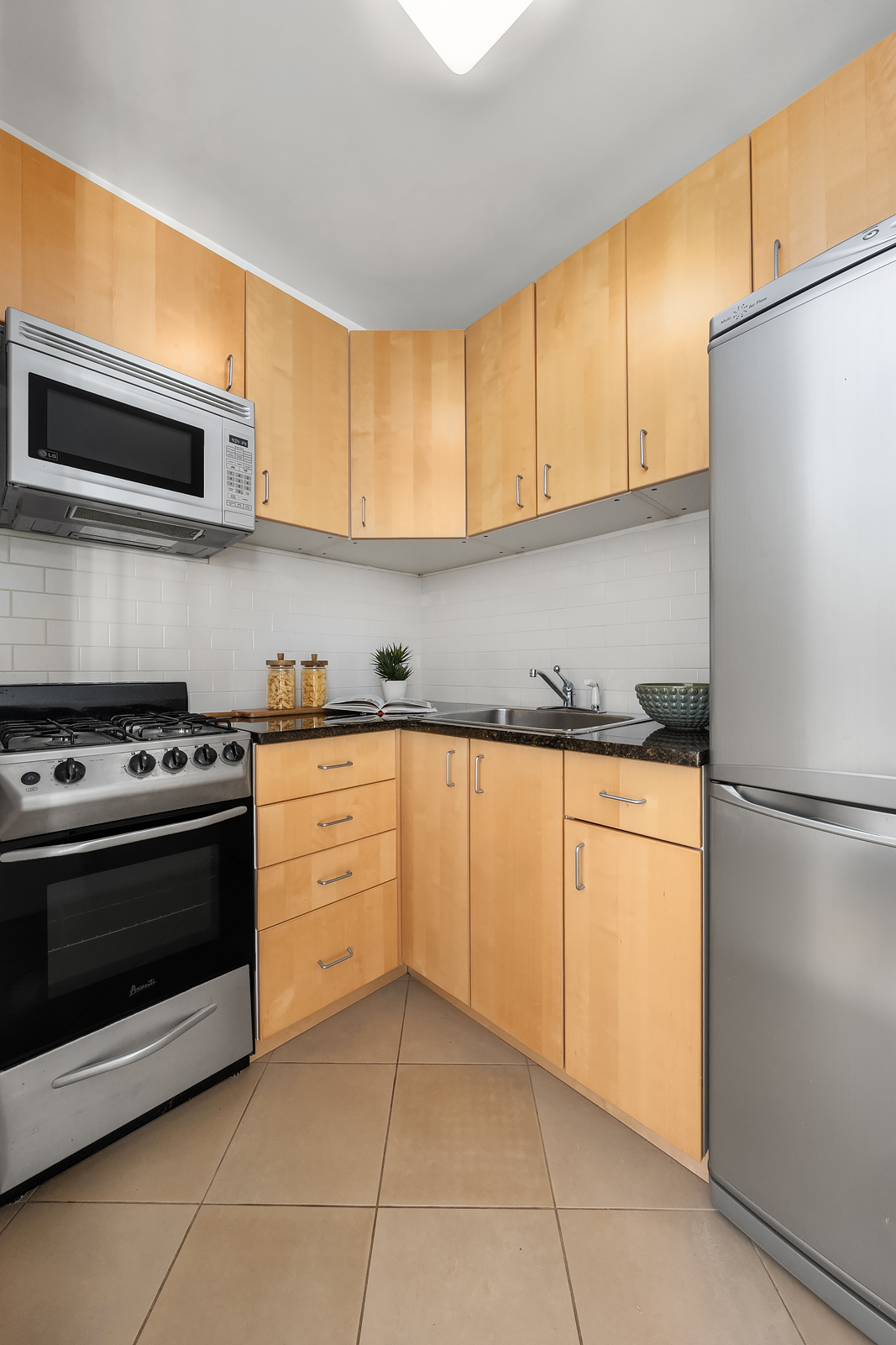 101 West 12th Street, Unit 10F Manhattan, NY 10011 - Photo 4 of 12 a kitchen with stainless steel appliances granite countertop a stove a refrigerator and a microwave