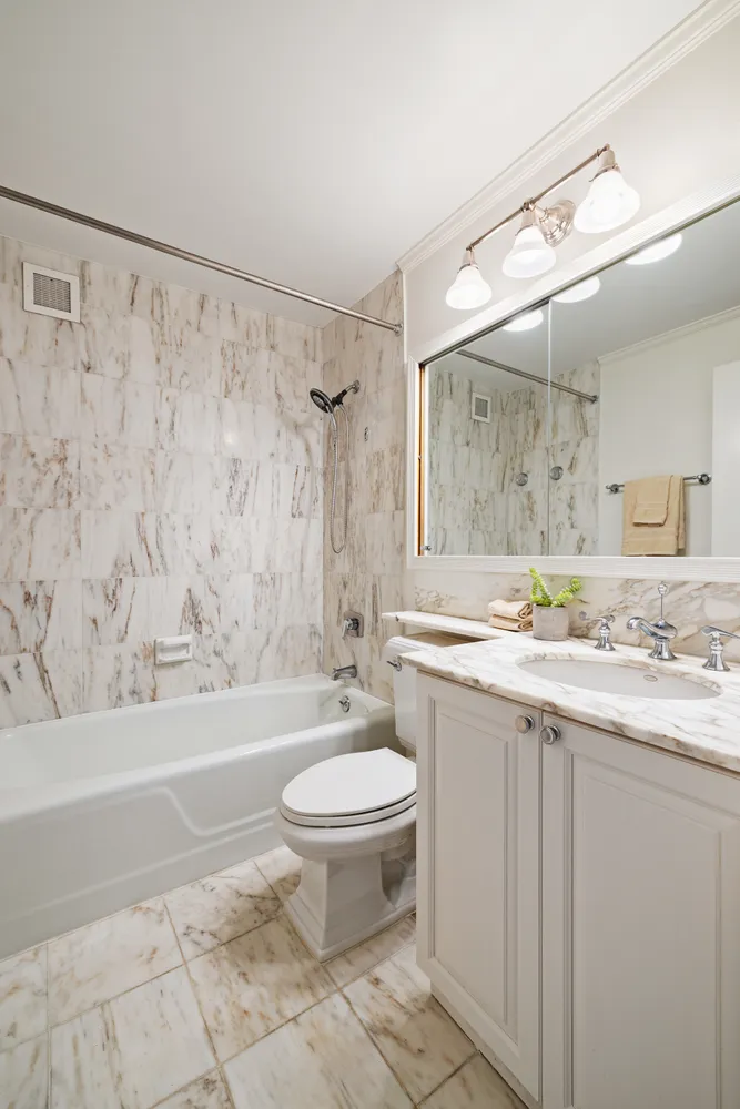 a bathroom with a granite countertop sink toilet a mirror a bathtub and shower
