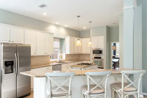 a kitchen with a refrigerator a stove a sink and white cabinets with wooden floor