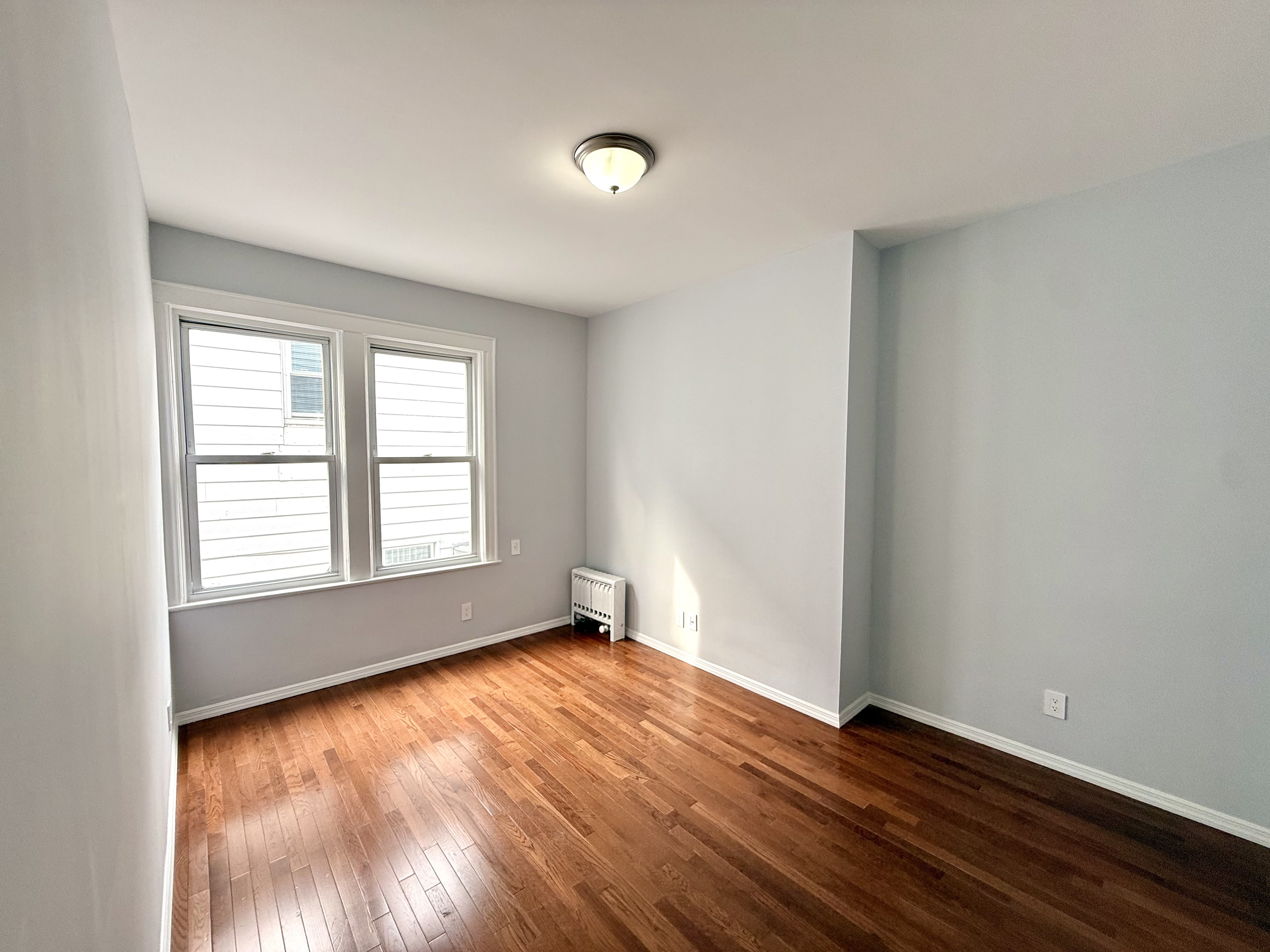 1675 85th Street, Unit 2R Brooklyn, NY 11214 - Photo 3 of 6 an empty room with wooden floor and windows
