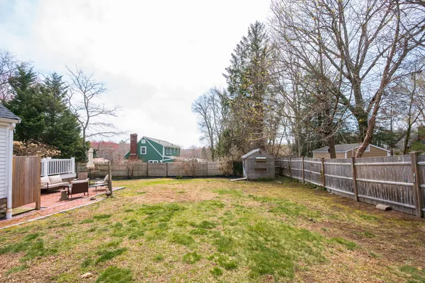a backyard of a house with table and chairs and wooden fence