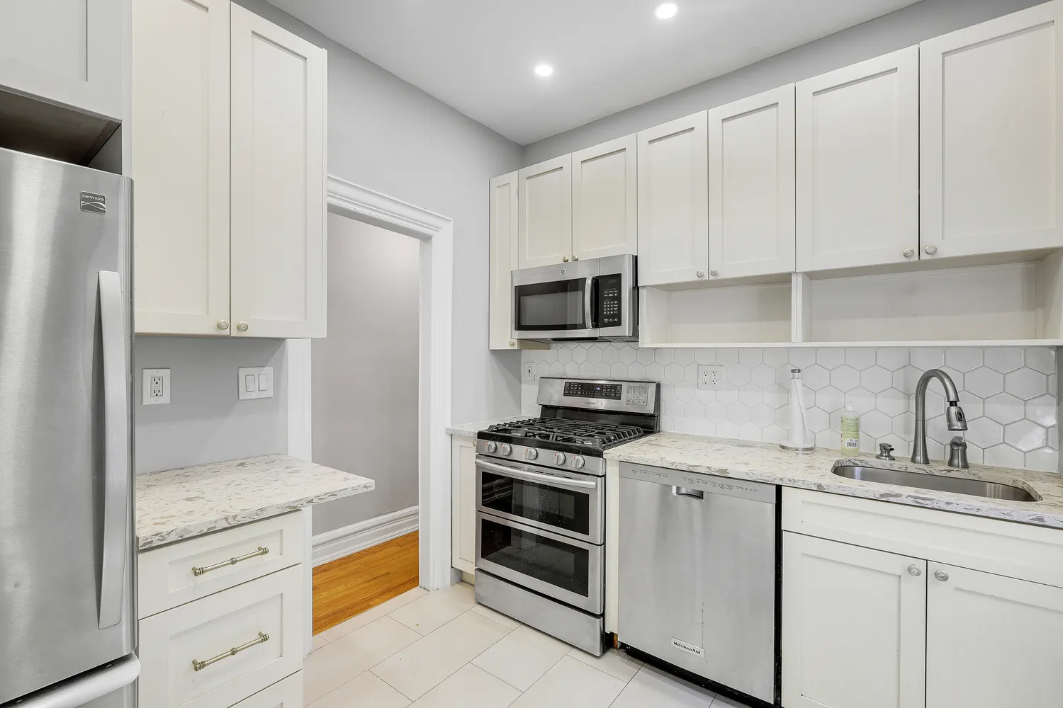 a kitchen with granite countertop white cabinets and stainless steel appliances