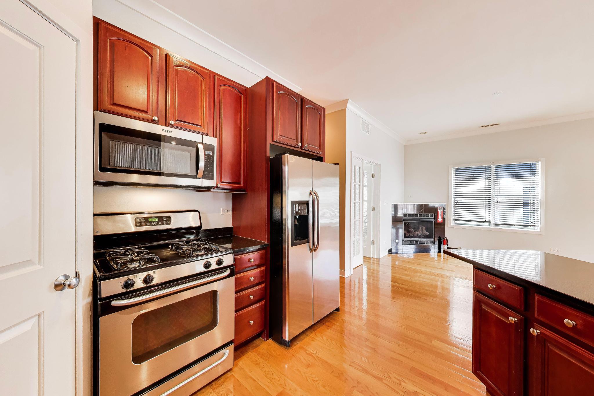 4845 North Springfield Avenue, Unit 2 Chicago, IL 60625 - Photo 11 of 32 a kitchen with stainless steel appliances a stove a microwave and wooden cabinets