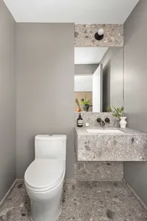 a bathroom with a granite countertop toilet sink and mirror