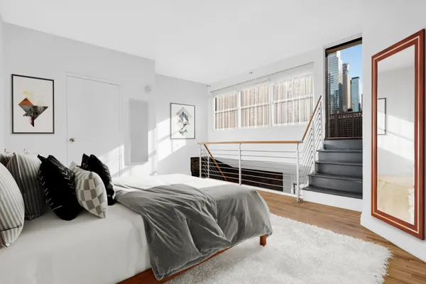 a bedroom with a bed and a dresser with wooden floor