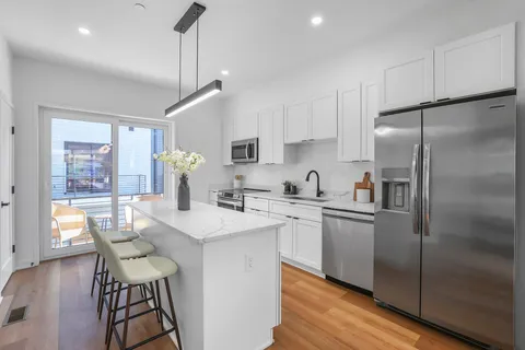 a kitchen with stainless steel appliances granite countertop a refrigerator a sink dishwasher a stove and white cabinets with wooden floor