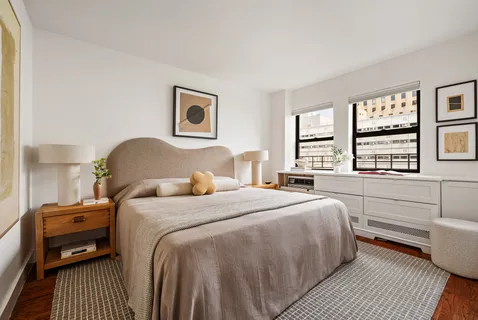 a bedroom with a bed and a large window with wooden floor