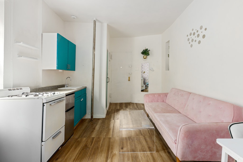 427 East 6th Street, Unit 1R Manhattan, NY 10009 - Photo 3 of 8 a living room with a couch and a stove with wooden floor
