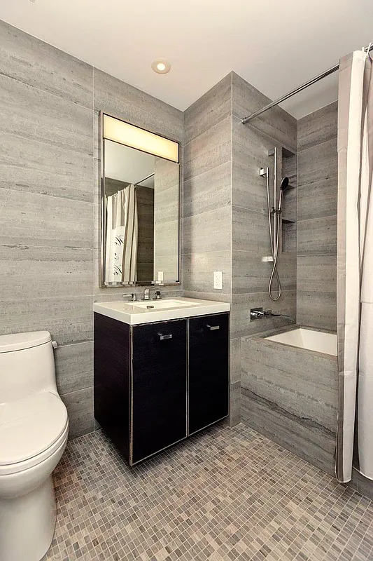 252 South Street, Unit 52J Manhattan, NY 10002 - Photo 7 of 17 a bathroom with a bathtub shower sink mirror and toilet