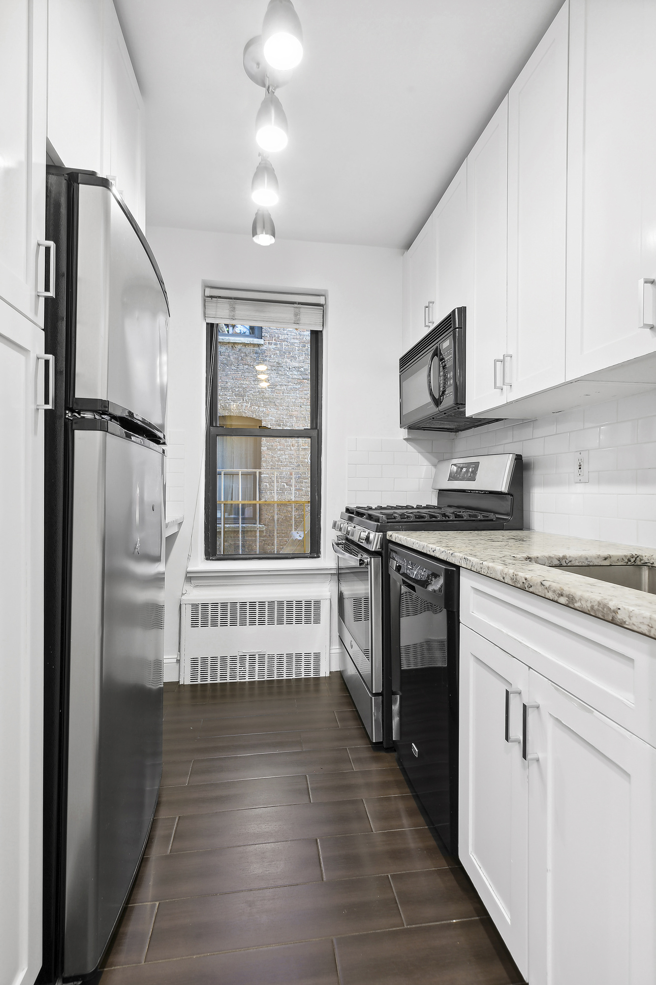 157 East 18th Street, Unit 4H Manhattan, NY 10003 - Photo 3 of 7 a kitchen with stainless steel appliances granite countertop a stove top oven a refrigerator a sink and white cabinets with wooden floor