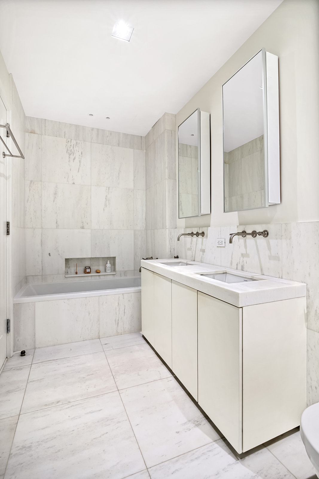 101 Wall Street, Unit 10C Manhattan, NY 10005 - Photo 7 of 15 a bathroom with a double vanity sink a mirror and a bathtub