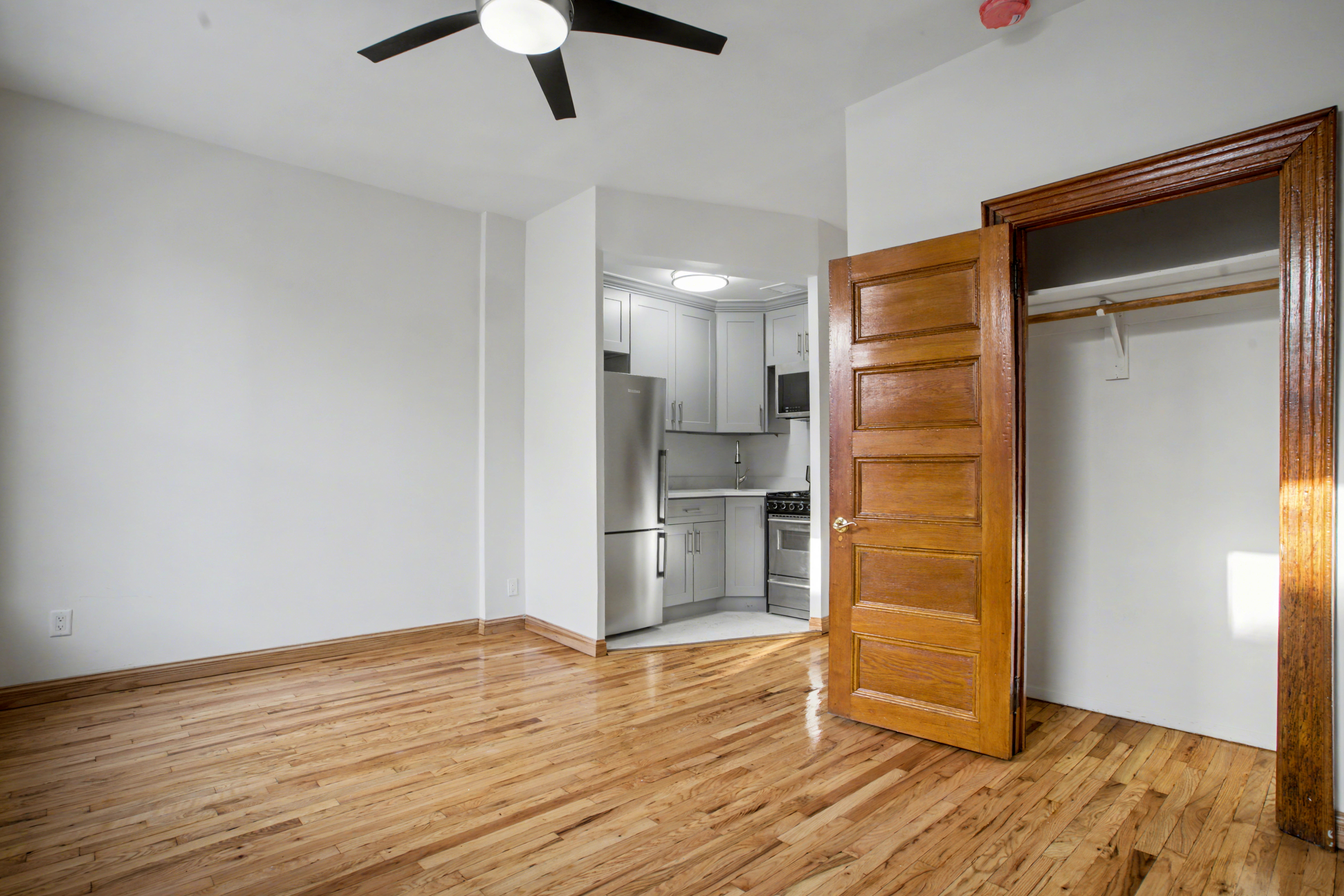 247 West 123rd Street, Unit 2F Manhattan, NY 10027 - Photo 7 of 9 wooden floor in an empty room with a kitchen