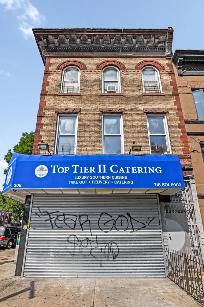 a view of a brick building with a red door and a bench