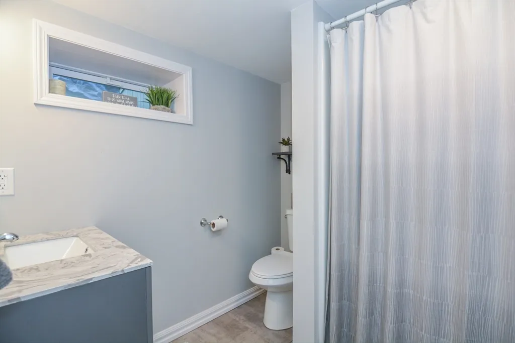 a bathroom with a toilet a sink and curtain