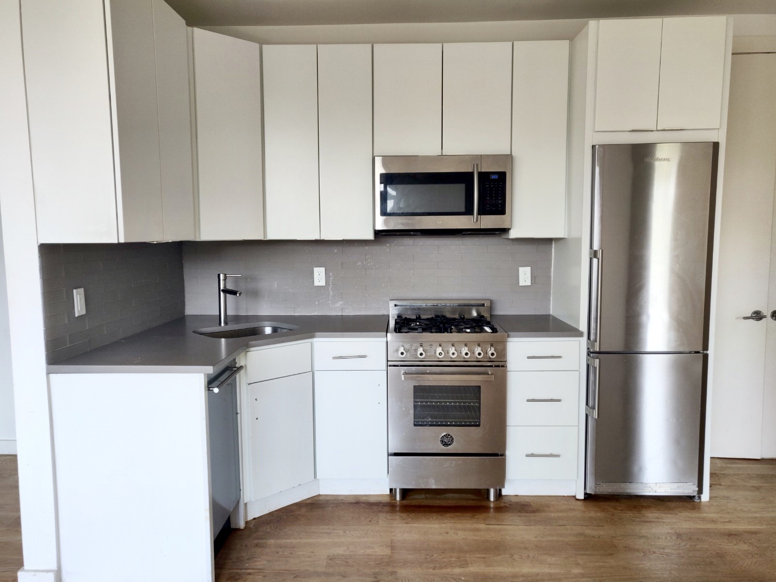 a kitchen with stainless steel appliances a refrigerator stove and white cabinets