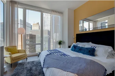 a bedroom with a bed couch and a larger window