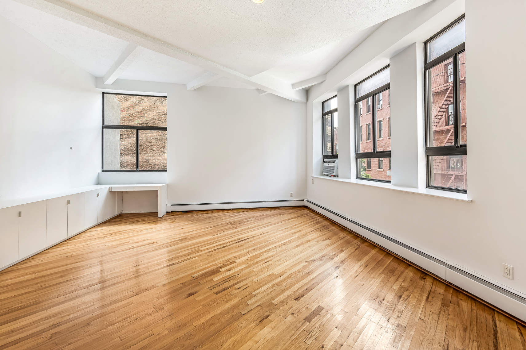 2 Cornelia Street, Unit 306 Manhattan, NY 10014 - Photo 4 of 13 a view of an empty room with wooden floor and a window