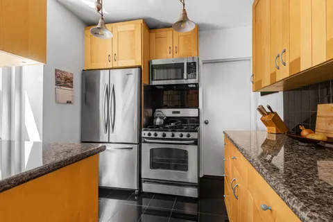 a kitchen with stainless steel appliances granite countertop a refrigerator a stove and a sink