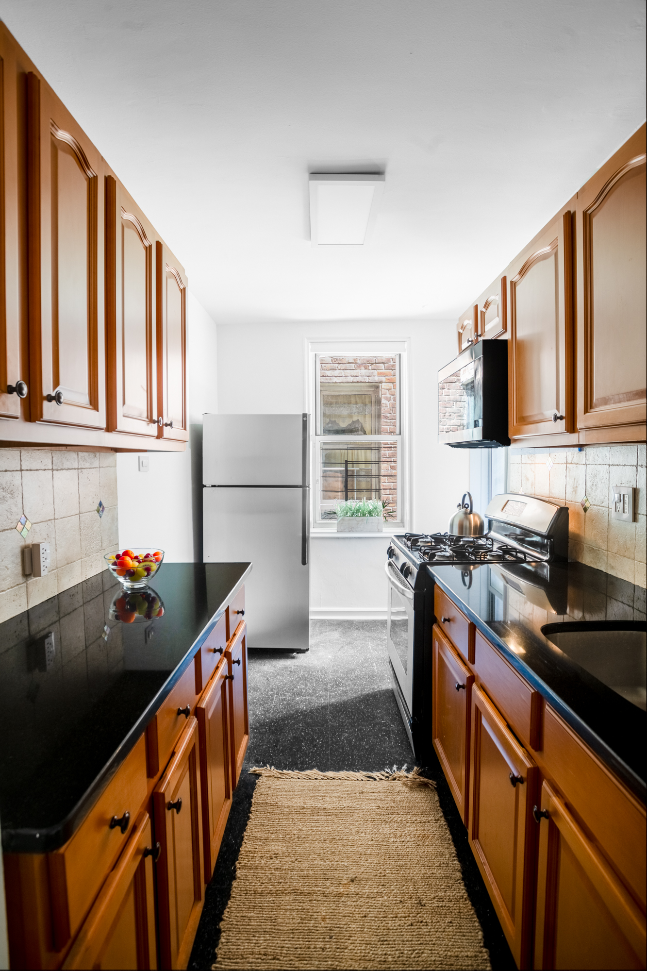 340 Haven Avenue, Unit 2H Manhattan, NY 10033 - Photo 4 of 24 a kitchen with stainless steel appliances a sink stove top oven and cabinets