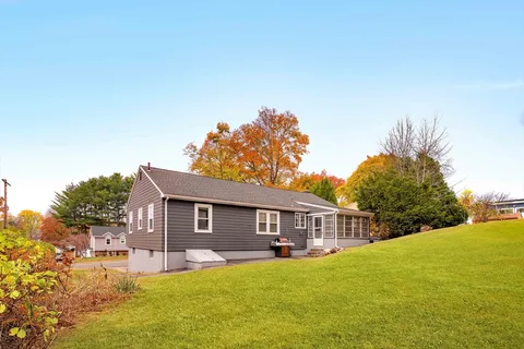 a front view of house with yard and trees in the background