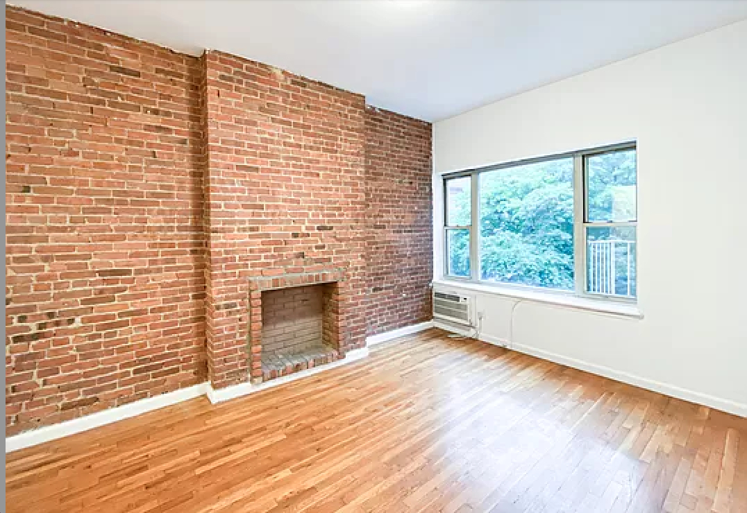 a view of empty room with wooden floor and fireplace