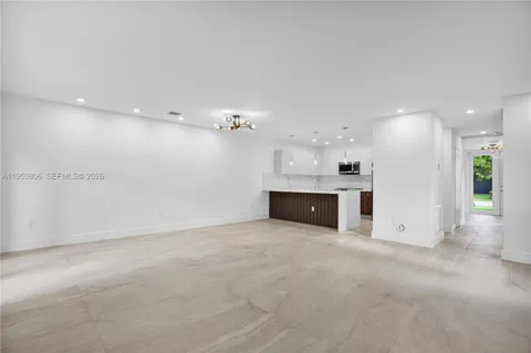 an empty room with kitchen view and a fireplace