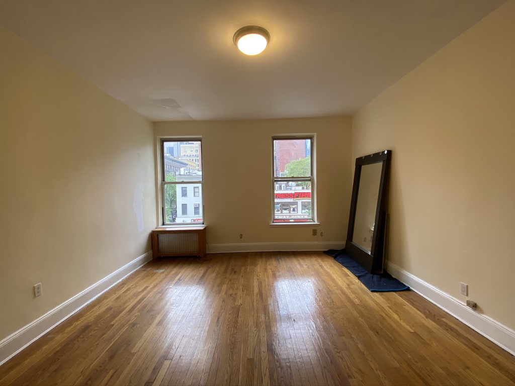 619 9th Avenue, Unit 3E Manhattan, NY 10036 - Photo 3 of 22 an empty room with windows and wooden floor