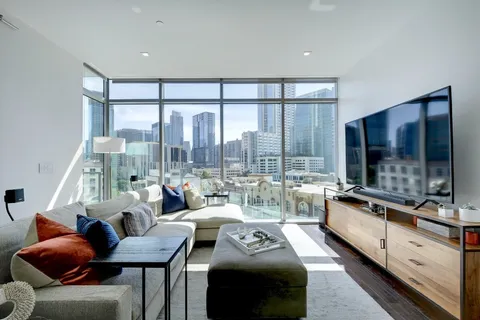 a living room with furniture flat screen tv and a large window