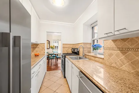 a kitchen with stainless steel appliances granite countertop a refrigerator a sink and white cabinets