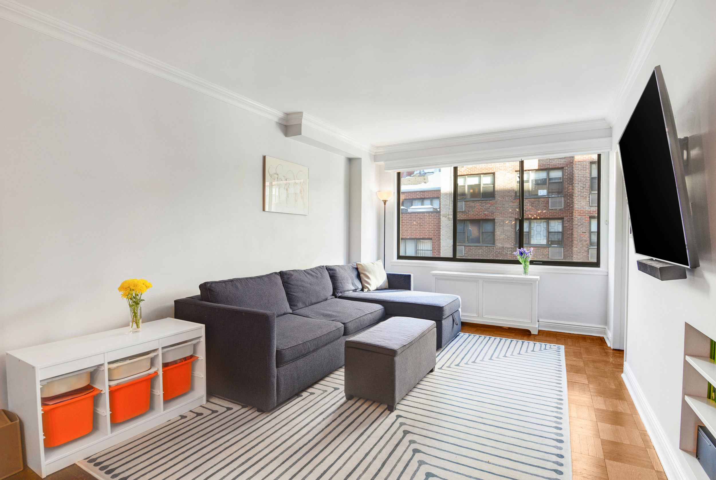 345 East 73rd Street, Unit 7J Manhattan, NY 10021 - Photo 3 of 13 a living room with furniture and a flat screen tv