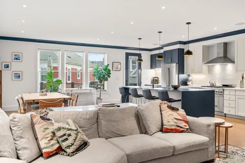 a living room with furniture kitchen and a large window