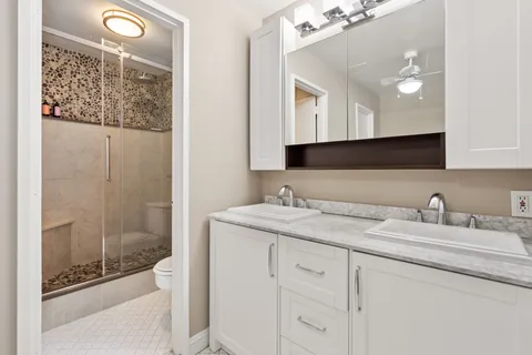 a bathroom with a granite countertop sink a mirror and shower