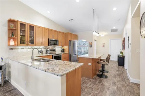 a large kitchen with granite countertop a large counter top appliances and cabinets