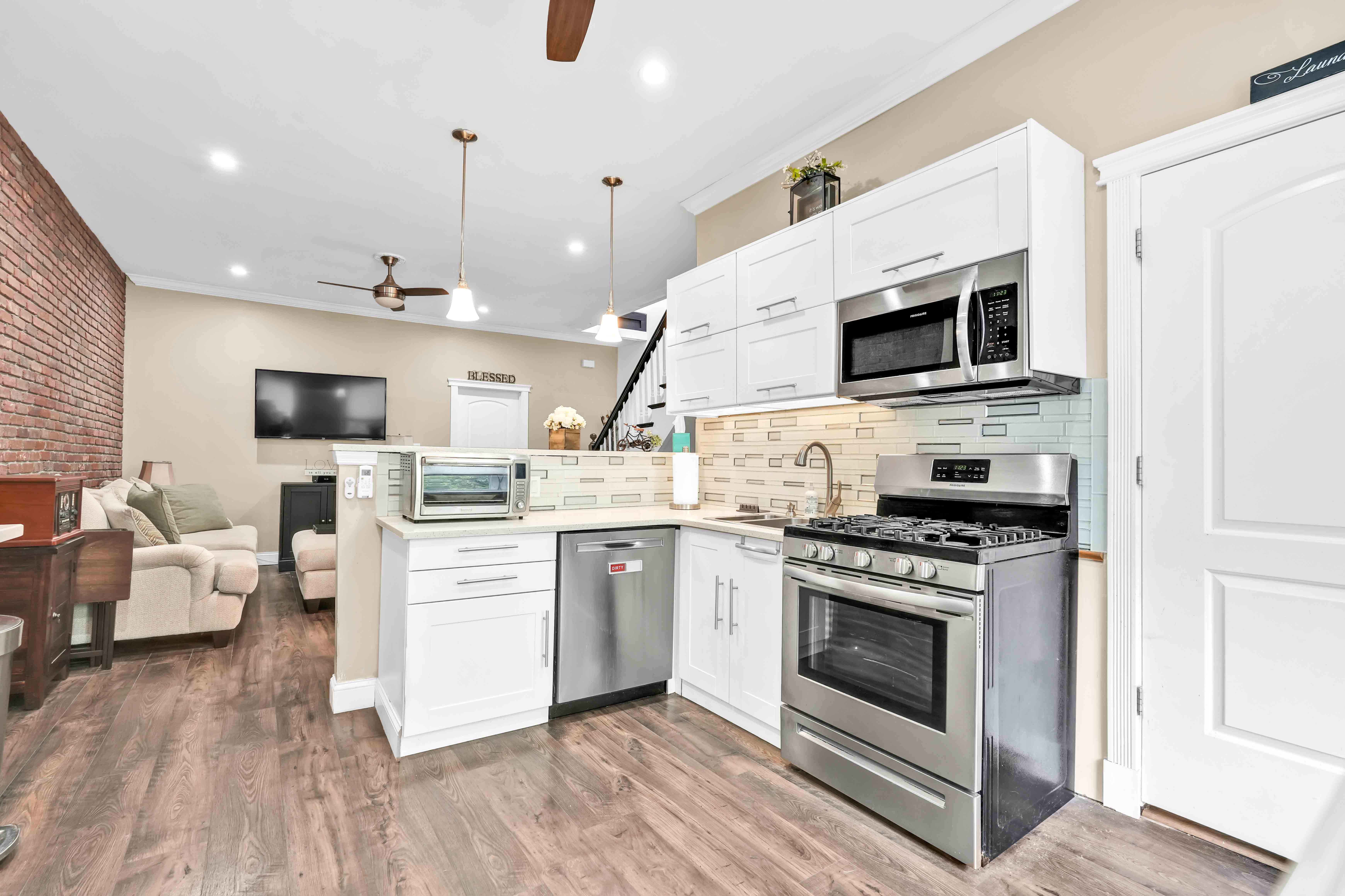 519 Monroe Street Brooklyn, NY 11221 - Photo 10 of 55 a kitchen with a stove a microwave oven a sink dishwasher and white cabinets with wooden floor