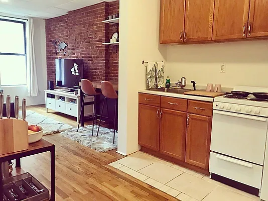 a living room with stainless steel appliances furniture a rug and a wooden floor