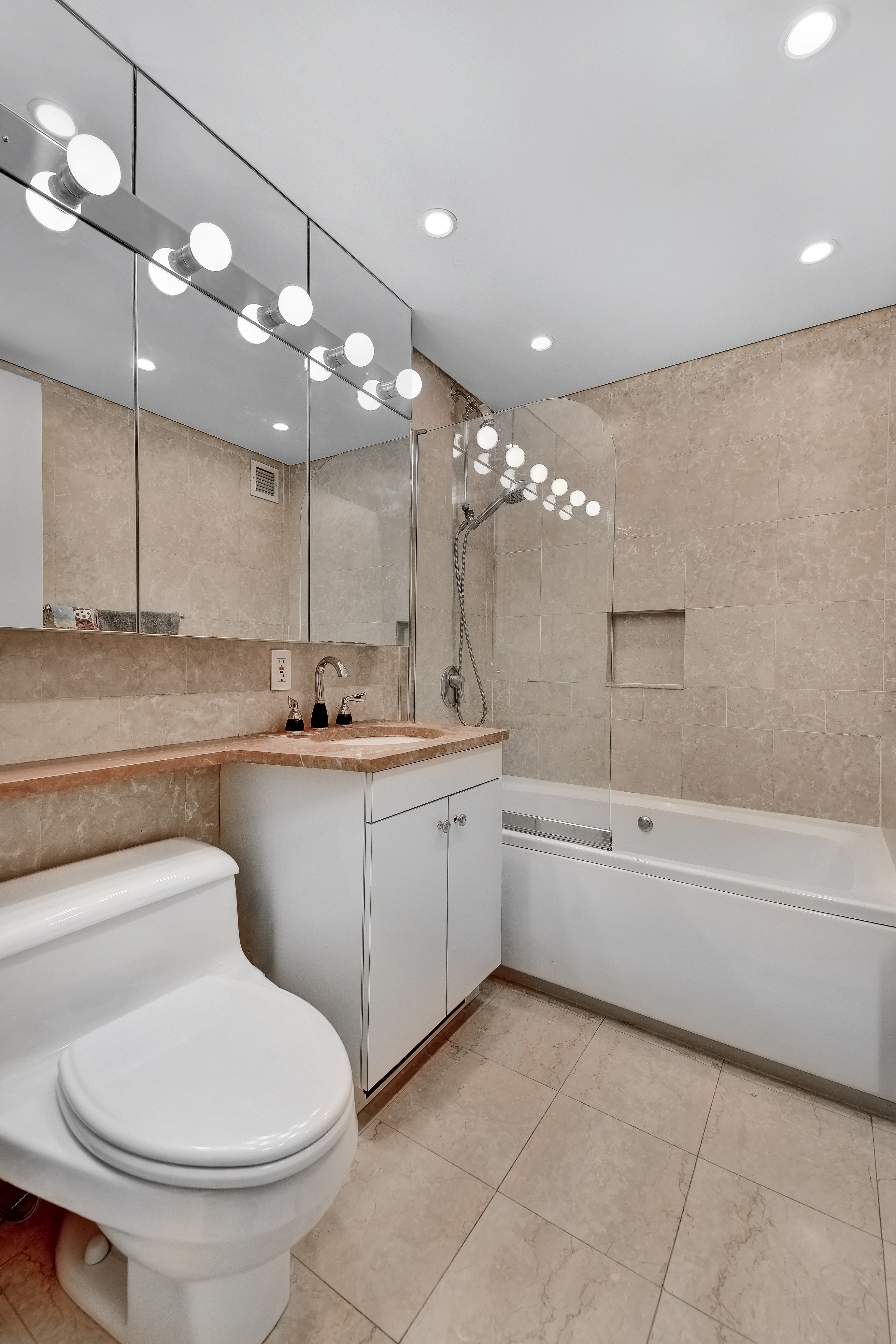 52 Park Avenue, Unit 5 Manhattan, NY 10016 - Photo 7 of 12 a bathroom with a toilet a sink a bathtub a mirror and shower