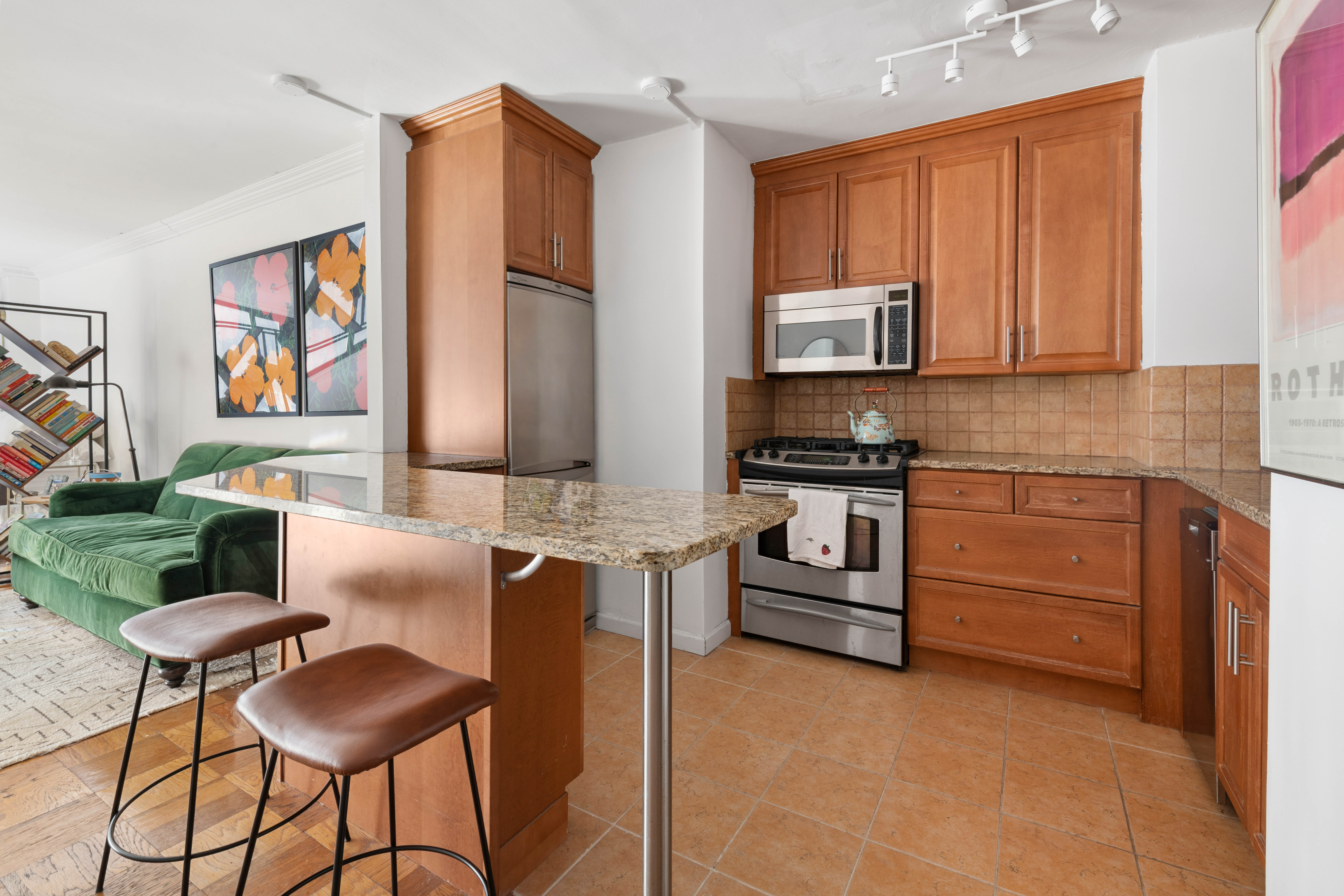 130 East 18th Street, Unit 10M Manhattan, NY 10003 - Photo 5 of 8 a kitchen with stainless steel appliances granite countertop a stove top oven a sink a dining table and chairs with wooden floor