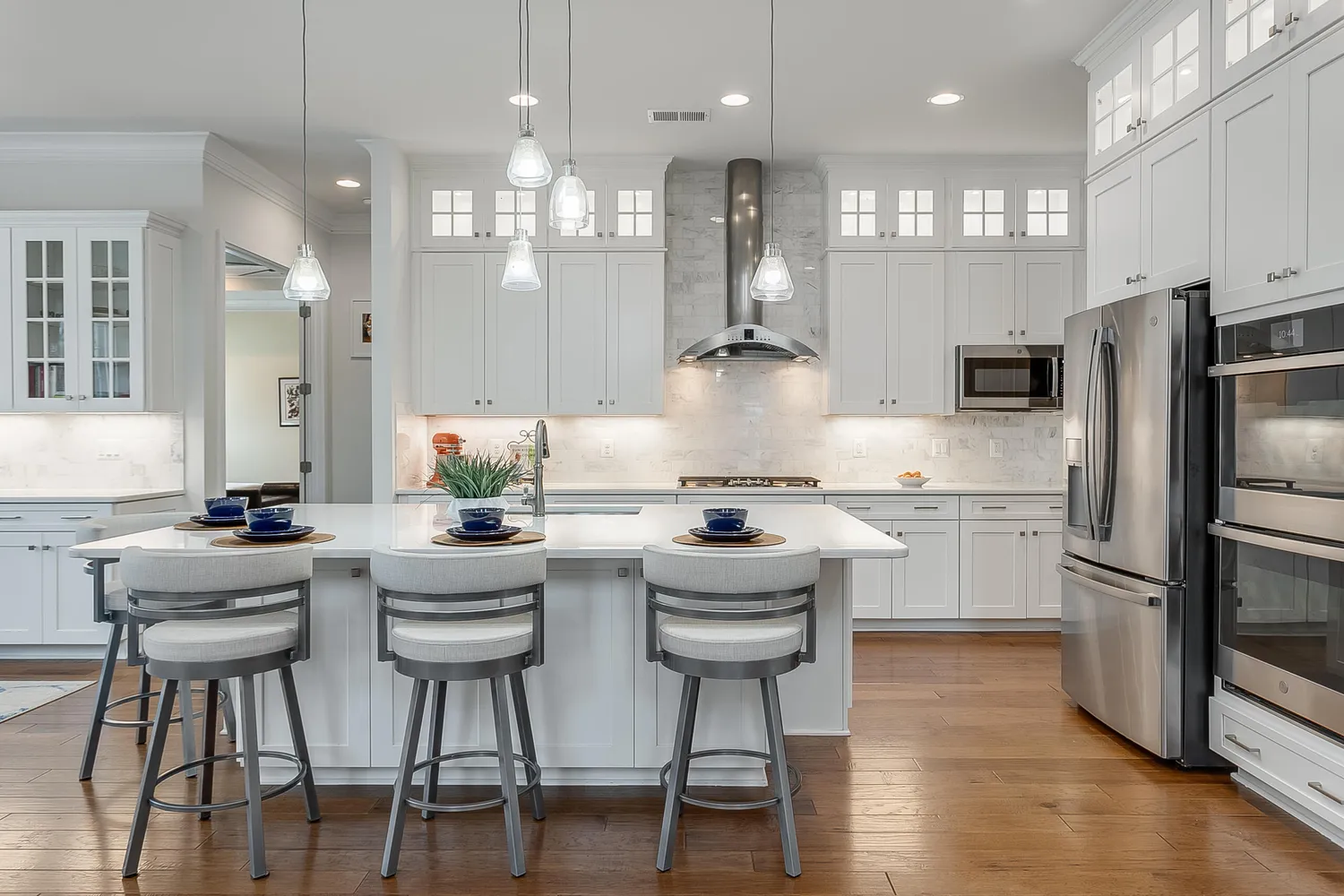 a kitchen with stainless steel appliances kitchen island granite countertop a dining table chairs refrigerator sink and cabinets