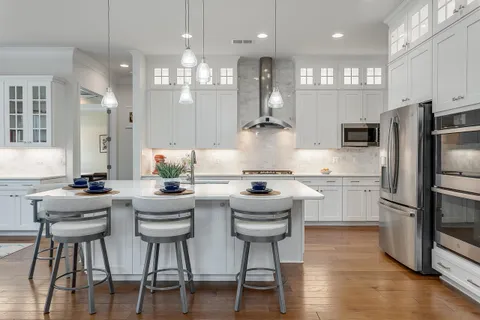 a kitchen with stainless steel appliances kitchen island granite countertop a dining table chairs refrigerator sink and cabinets