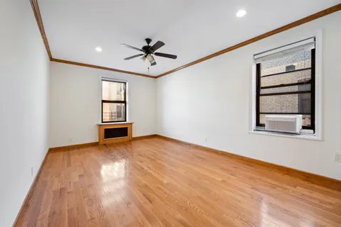 a view of empty room with wooden floor and fan