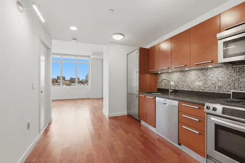 a kitchen with stainless steel appliances granite countertop a refrigerator a stove top oven a sink and dishwasher with wooden floor