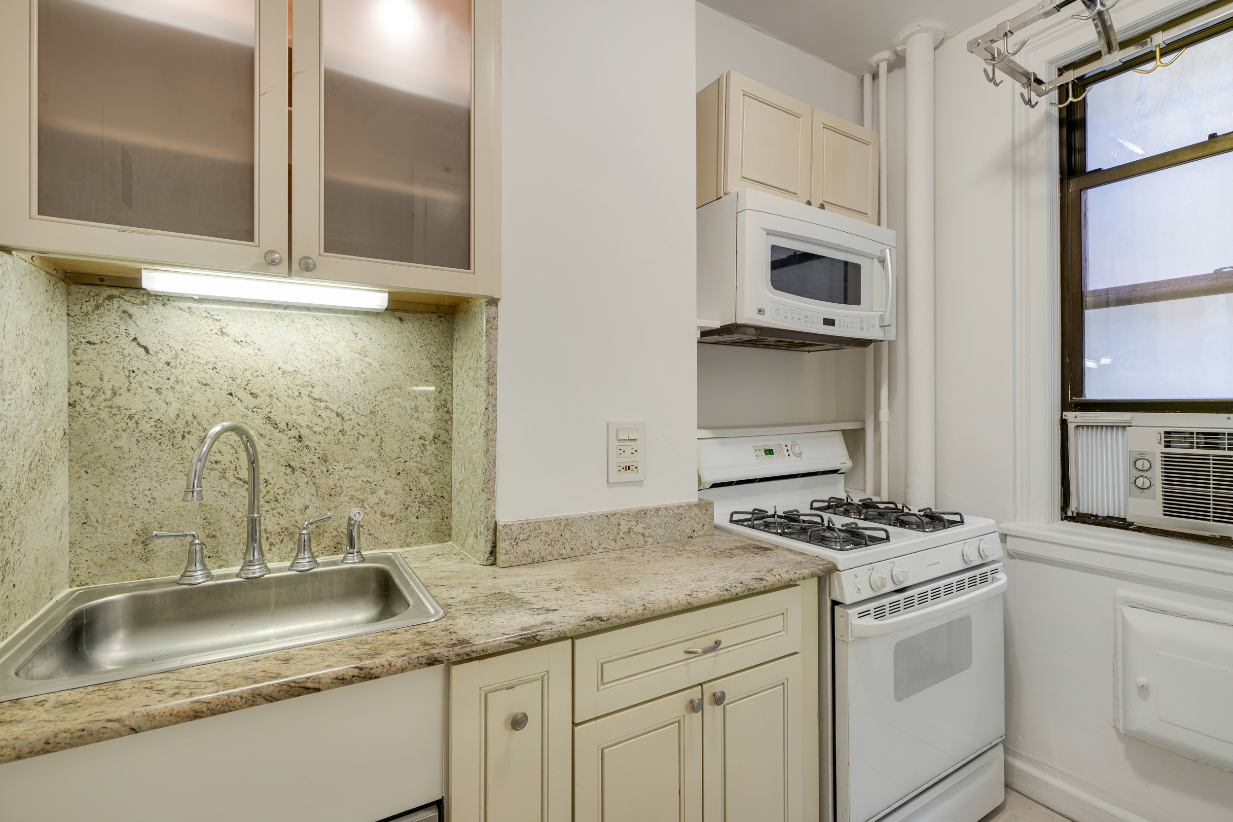 74 West 68th Street, Unit 5A Manhattan, NY 10023 - Photo 6 of 25 a kitchen with granite countertop a sink stove and cabinets