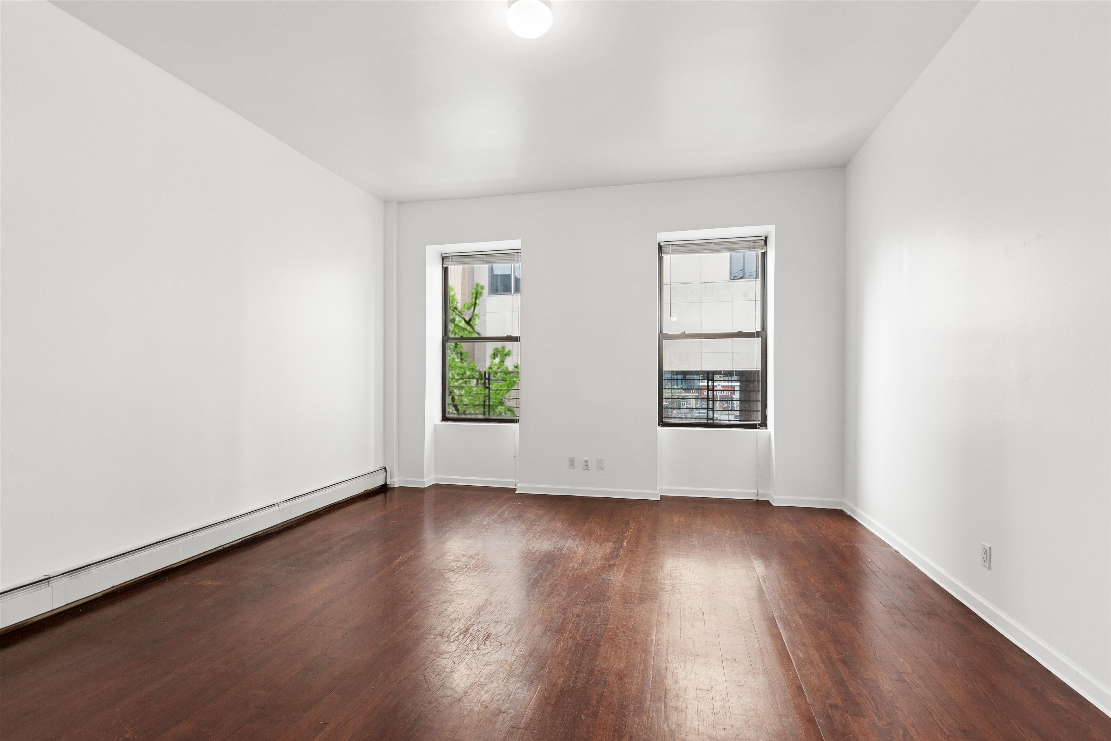 165 West 126th Street Manhattan, NY 10027 - Photo 25 of 40 an empty room with wooden floor and windows
