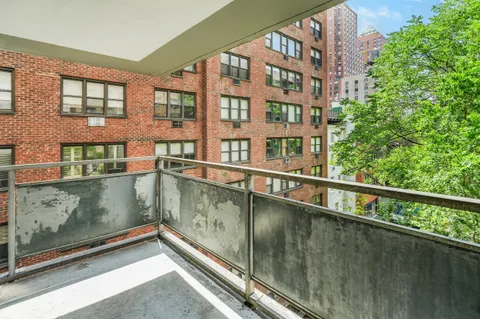 a view of balcony with a couple of cars parked in front of house