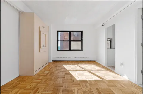 a view of an empty room with window and bathroom