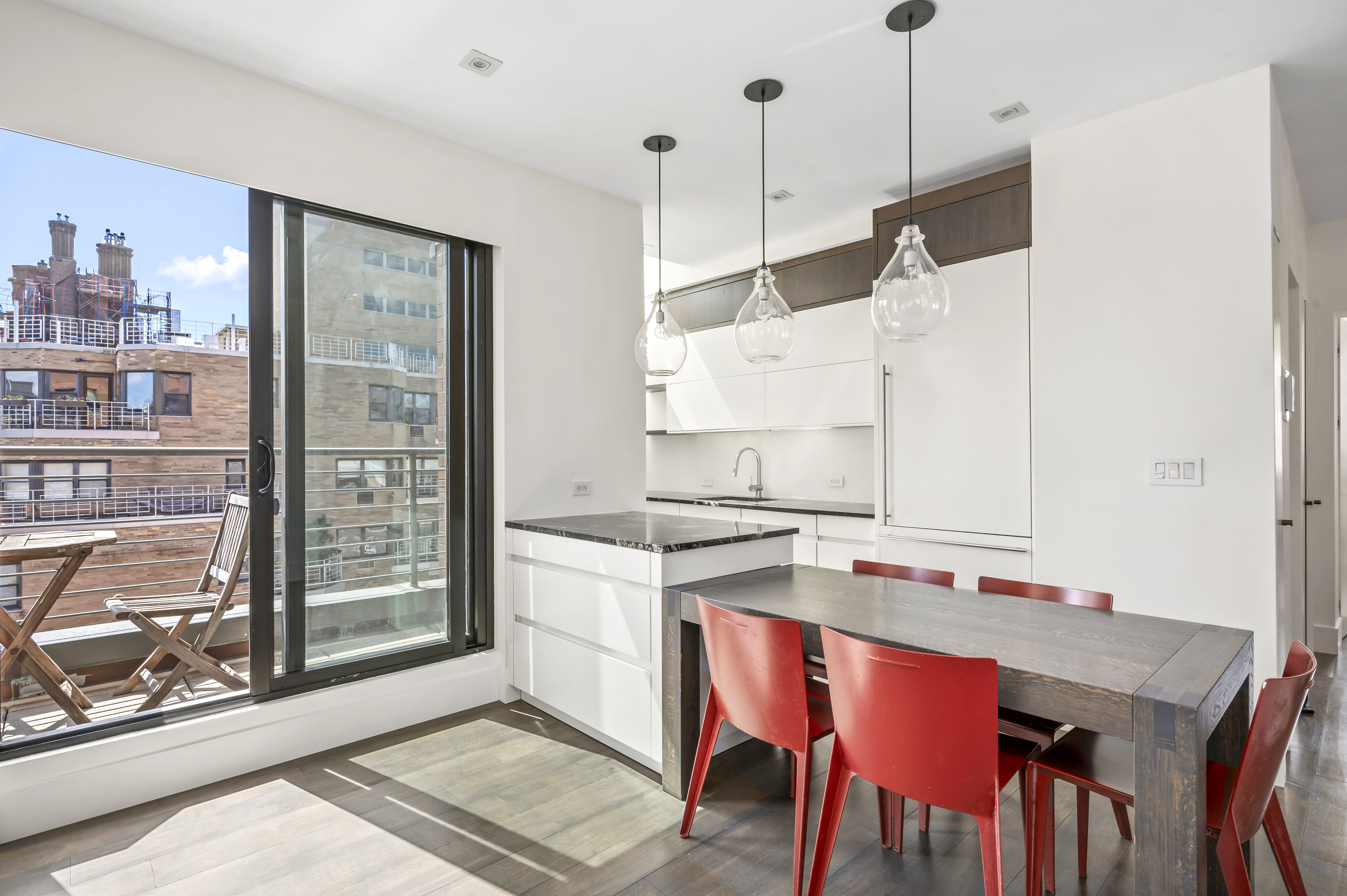 131 East 81st Street, Unit PH15 Manhattan, NY 10028 - Photo 5 of 11 a open kitchen with stainless steel appliances granite countertop a stove a refrigerator a sink dishwasher with a dining table and chairs