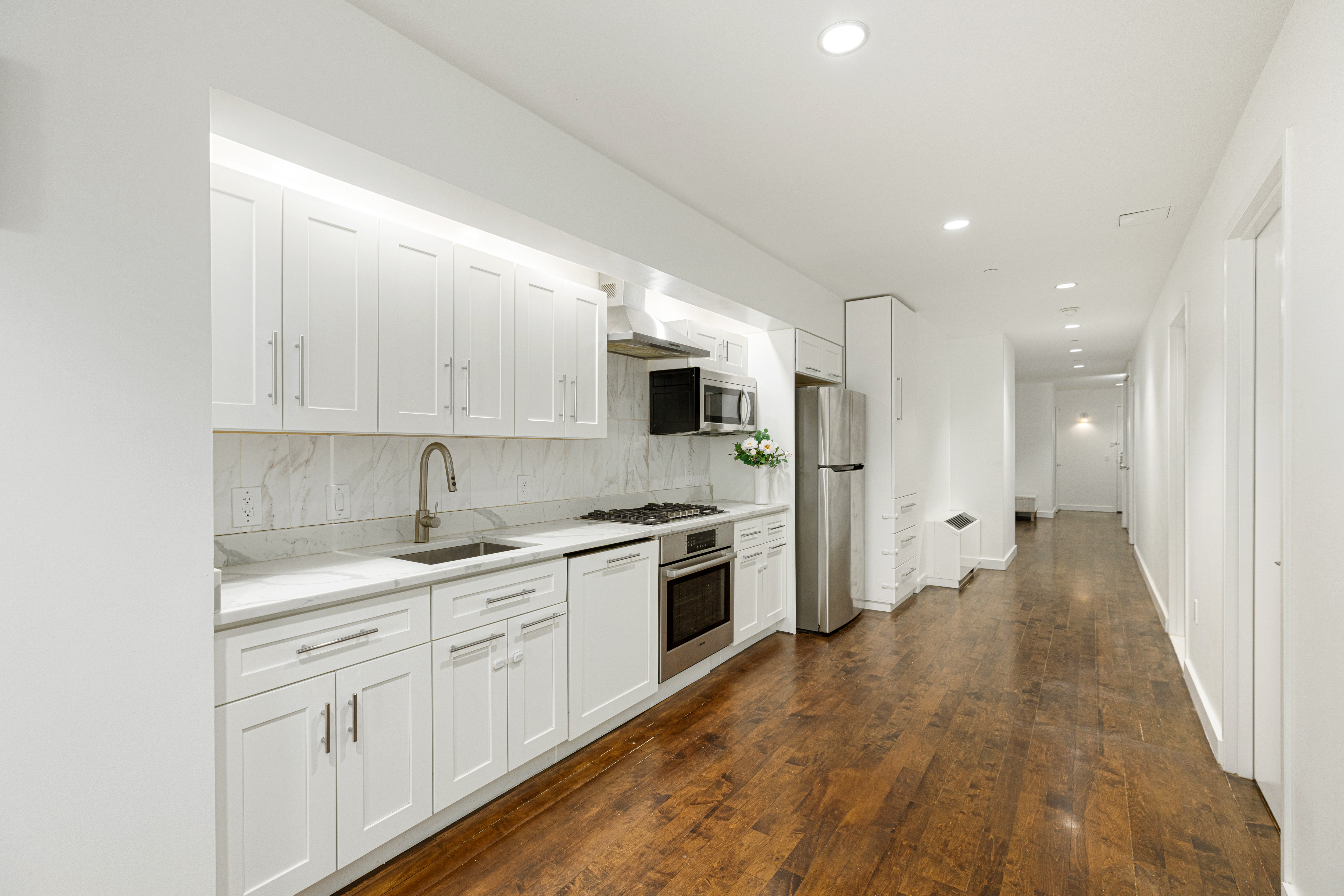 15 Broad Street, Unit 2300 Manhattan, NY 10005 - Photo 5 of 36 a kitchen with white cabinets and stainless steel appliances